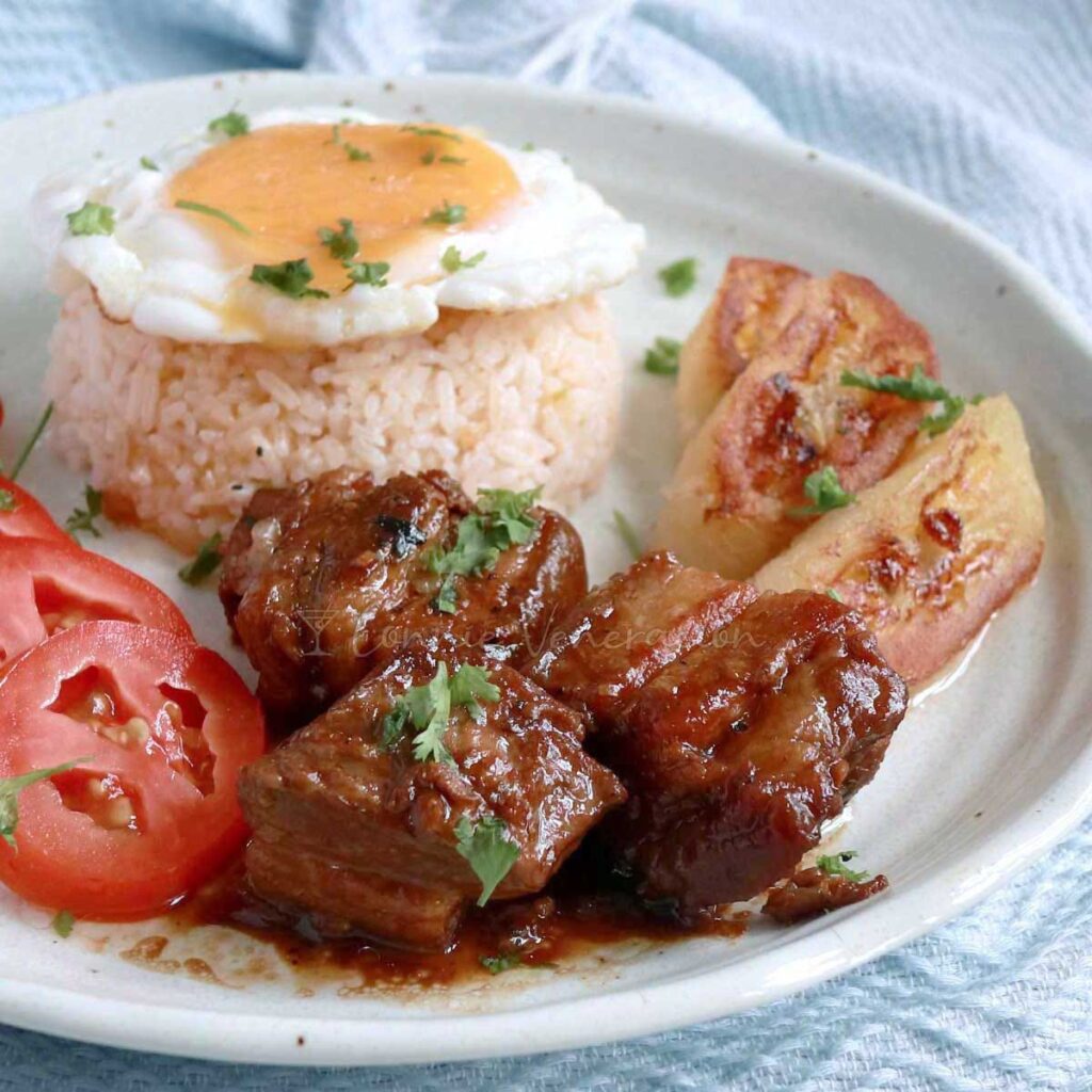 Slow cooker pork adobo served with rice, egg, tomato slices and fried bananas